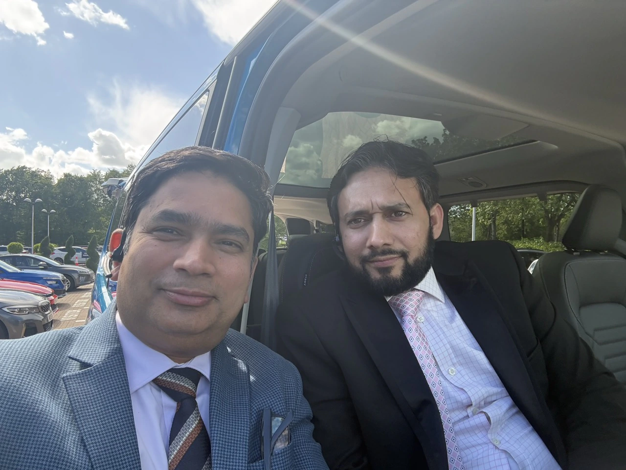 Two professional chauffeurs beside a Ford Tourneo passenger vehicle at a brand event